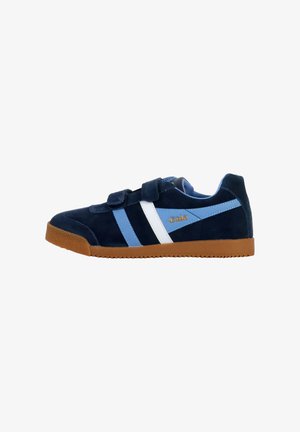 Zapatilla de ante azul con franjas blancas y azul claro, con correas de Velcro y suela de goma. Logo de la marca en dorado en el costado.