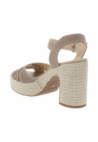 Sandalo con tacco alto in suede beige, con una piattaforma intrecciata e un tacco a blocco testurizzato. Presenta un design con ritagli e una cinghia alla caviglia regolabile.