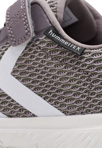 Grüner und lila Sportsschuh mit Obermaterial aus Mesh, weißen Streifen und Klettverschluss. Verfügt über ein strukturiertes, gewebtes Design und eine Gummisohle.