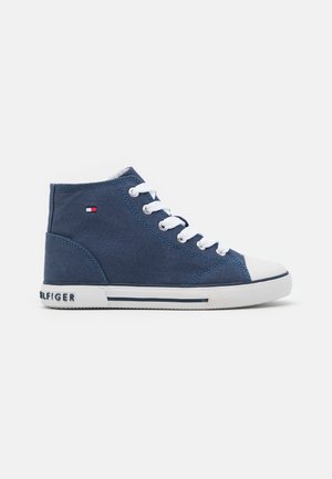 Baskets montantes bleu marine avec lacets blancs, embout et semelle en caoutchouc, avec un petit logo drapeau rouge, blanc et bleu sur le côté.