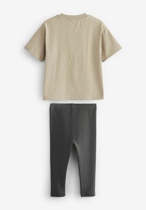 Béžové bavlnené tričko s krátkym rukávom a okrúhlym výstrihom, kombinované s priliehavými čiernymi legínami z textúrovanej látky.