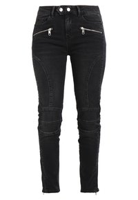 Vaqueros skinny de mezclilla negra con bolsillos con cremalleras plateadas, detalles de costura sutil y acentos de cremallera en el tobillo para un diseño añadido.
