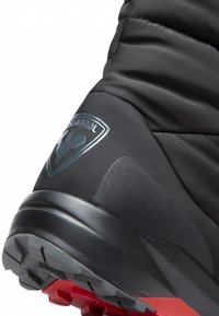 Svarta vadderade vandringskängor med en texturerad gummisula. Har en logotyp på sidan och en kontrasterande röd sula för bättre grepp.