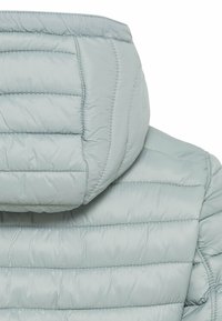 Chaqueta acolchada tipo puffer de color gris claro que muestra la parte trasera con costuras horizontales y una capucha adjunta.