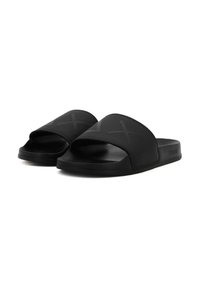 Black slide sandals with a wide front strap, featuring a textured surface and X-shaped pattern. Flat sole, minimalist design, and smooth finish.