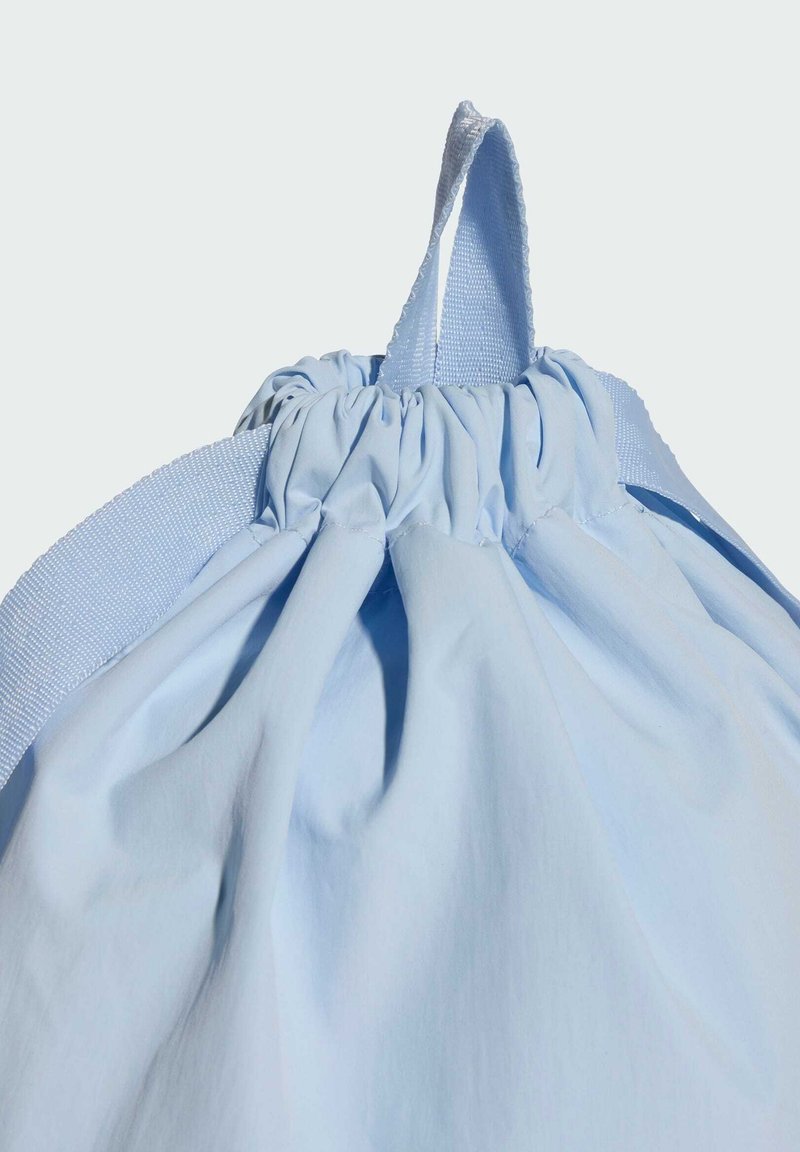 Borsa a coulisse azzurro chiaro realizzata in tessuto morbido, con apertura superiore arricciata, tracolla texturizzata e manico ad anello per un trasporto facile.