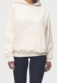 Sudadera con capucha color crema en tejido suave con bolsillo delantero, puños y bajo acanalados; cuenta con capucha con cordón y diseño minimalista.