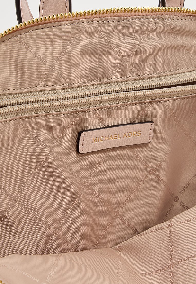 Lichtbeige Michael Kors handtas interieur met gewatteerde stof, gouden rits en een merklabel. Duurzaam nylon materiaal en een strakke design.