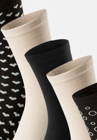 Fire par sokker: sorte, beige, og mønstrede i neutrale toner. Ribbet tekstur, varierende design herunder prikker og hjerter.