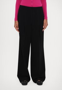 Zwarte wijde broek met een trekkoord in de taille, gemaakt van een gladde, lichte stof. Beschikt over dubbele plooien en een relaxed fit.