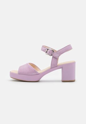 Lavendel farvet sandal med blokhæl, åben tå, ankelrem og sølvspænde på hvid baggrund.