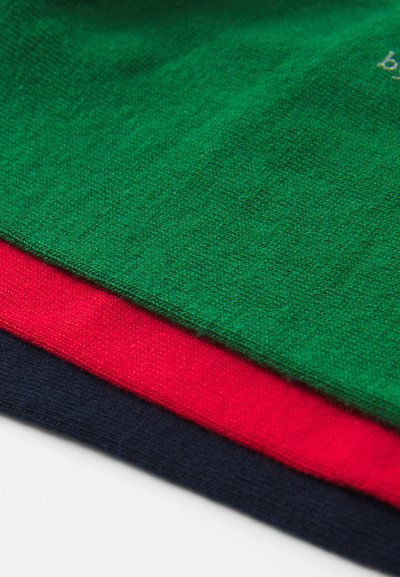 Trīs salocītu adīto audumu paraugi zaļā, sarkanā un tumši zilā krāsā, demonstrējot mīkstu tekstūru un gludu apdari ar redzamām šķiedrām.