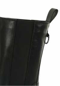 Črne usnjene gležnarske čevlje z elastičnimi stranskimi ploščami, zanka za držalo in šivanim detajlom za dodatno teksturo in oblikovanje.