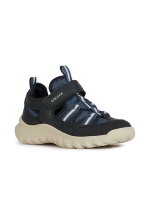 Chaussures en mesh bleu et synthétique avec une sangle Velcro, présentant des accents de rayures blanches et marines, et une semelle épaisse couleur crème.