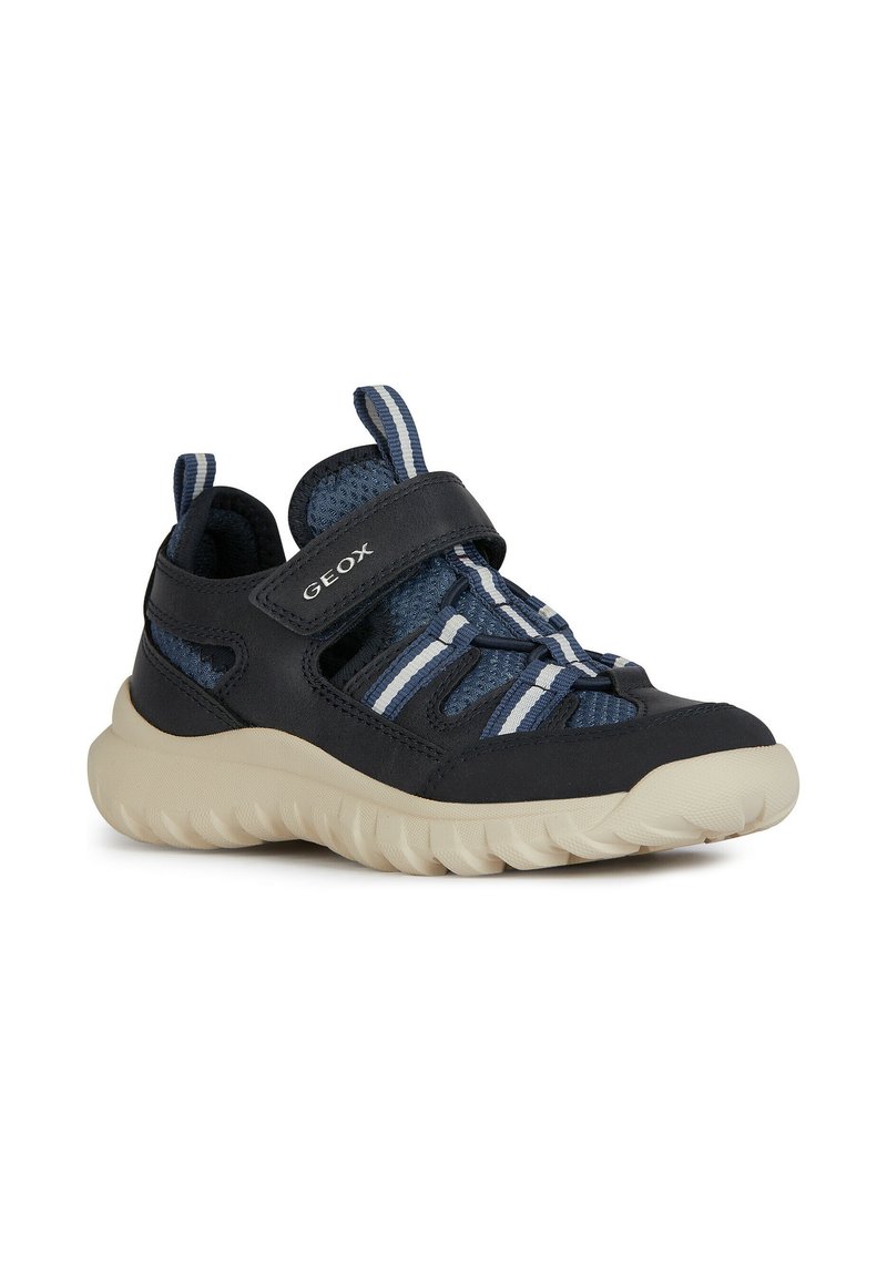 Zapatos de malla y sintéticos en azul con una correa de Velcro, que presentan acentos a rayas blancas y marino, y una suela gruesa de color crema.
