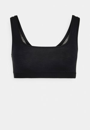 Svart, ermeløs bralette laget av mykt stoff. Har en scoop halslinning og et bredt bånd nederst for støtte.