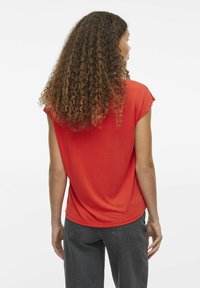 Camiseta corta de manga roja, confeccionada en material suave, ajuste relajado, cuello redondo, diseño liso, combinada con pantalones de pierna ancha gris oscuro.
