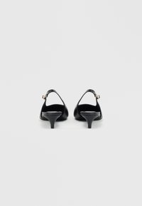 Mustad nahk slingback kontsad terava ninaga, madala koonuspeaga ja kuldse detailiga rihmal. Sujuv tekstuur.