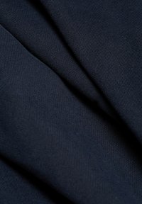Tissu bleu marine foncé avec une fine texture tricotée, présenté en plis doux et en détail rapproché.