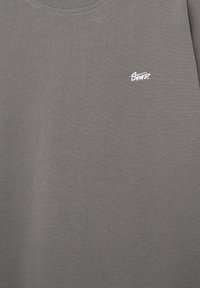 Sweat-shirt gris à col rond avec petit logo blanc brodé "SNITZ." sur la partie gauche de la poitrine.