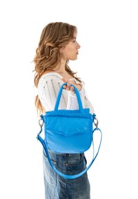 Kék, puha tapintású kézitáska két rövid fogantyúval és egy hosszú, állítható pánttal. Elöl kisebb zseb található, az oldalon pedig logó van gravírozva.