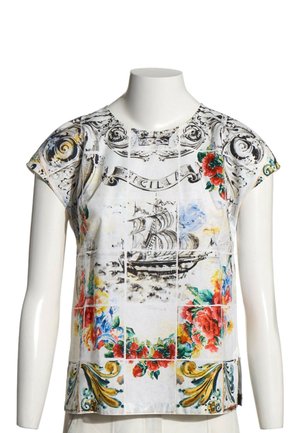 Chemise blanche à manches courtes avec des motifs floraux colorés, un voilier et des volutes décoratives sur un mannequin buste.