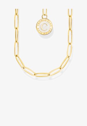 Złoty łańcuszek z wydłużonymi ogniwami i okrągłym medalikiem wygrawerowanym z "THOMAS SABO CHARM CLUB" wokół litery C na białym tle.