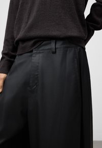 Svarta, högmidjade byxor med en slät, glänsande yta, med en rak front, sidofickor och en elegant design.