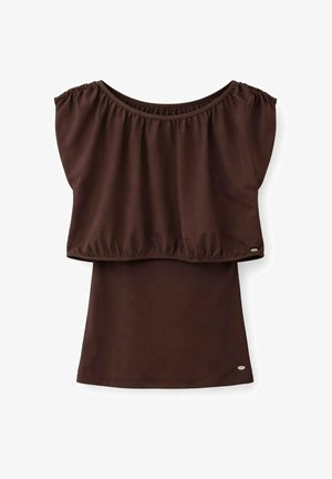 Bruine mouwloze top met brede geplooide volant-overlay en klein zilverkleurig merkembleem aan de zoom op witte achtergrond.