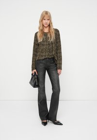 Mustad laiad teksad on paaritatud metallilise loomade mustriga bluusiga. Mudel hoiab musta käekotti ja kannab terava ninaga musti baleriini kingi.