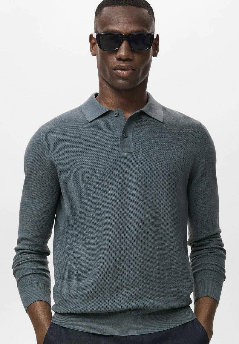 Light gray long-sleeve polo shirt in textured knit fabric, featuring a pointed collar and two-button placket, worn with dark sunglasses.