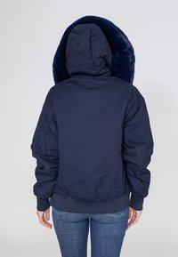 Navyblaue Daunenjacke mit einer großen, weichen, fellgefütterten Kapuze. Verfügt über schmale Bündchen und einen elastischen Saum, mit zusätzlichen Details an den Ärmeln.