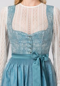 Traditionelles Kleid mit hellblauem gemustertem Oberteil, langen Spitzenärmeln und einem gesmokten Taillenbereich. Verfügt über eine gebundene Schleife an der Taille.