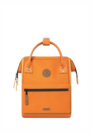 Orange fabric backpack with a structured design, featuring a top handle, a front zip pocket, and leather accents. Circular logo on front.