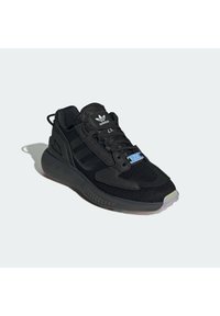 Black athletic shoe featuring mesh upper, three signature black stripes, textured sole, and distinct blue branding on the tongue.