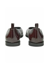 Chaussures en cuir bordeaux à enfiler avec une texture lisse, une forme arrondie, une semelle en caoutchouc noire contrastante et un petit tirant à l'arrière.