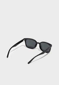 Ochelari de soare negri cu un cadru lat, lentile plate și brațe subțiri. Au un design minimalist cu finisaj lustruit și accente metalice.