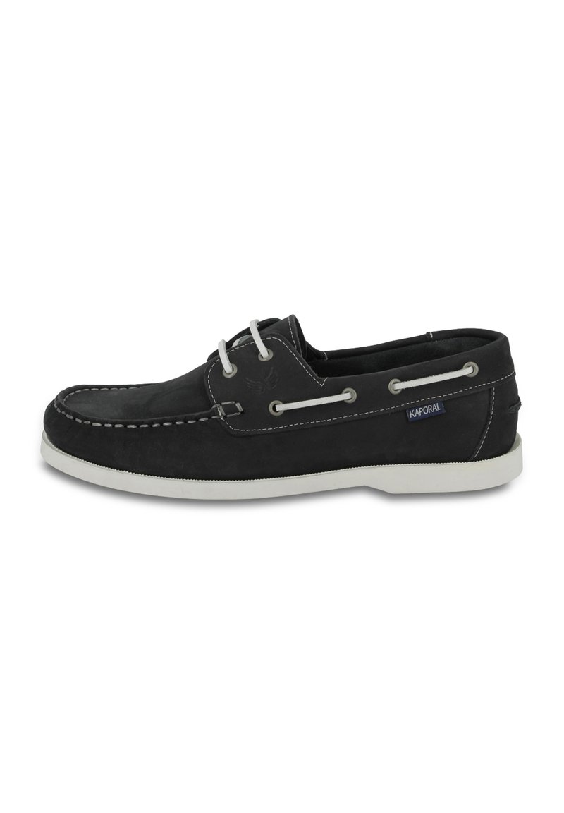 Zapato de barco de cuero negro con costuras y cordones blancos, con una suela de goma y una pequeña etiqueta azul en el lado.