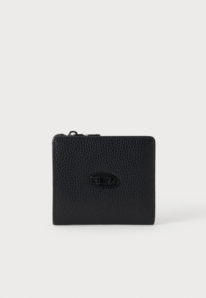 Portefeuille en cuir noir texturé avec fermeture éclair et petit badge ovale en métal avec logo au centre sur fond neutre.