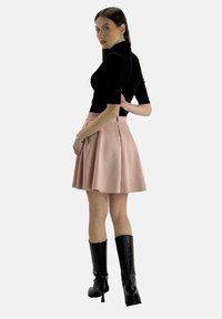 Top nero a maniche corte abbinato a una gonna rosa a campana con zip sul retro. La modella indossa stivali neri con tacco fino al ginocchio. Design semplice ed elegante.