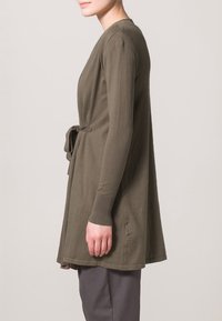 Olivgrön omlottskofta i mjukt tyg, med långa ärmar och ett knytbälte i midjan, med en avslappnad och flödande design.