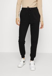 NA-KD PAMELA REIF x NA-KD - TRACKSUIT BOTTOMS - Calças de fato de treino - black