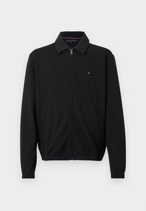 Black zip-up jacket with collar, long sleeves, side pockets, and small red, white, and blue logo on the left chest.