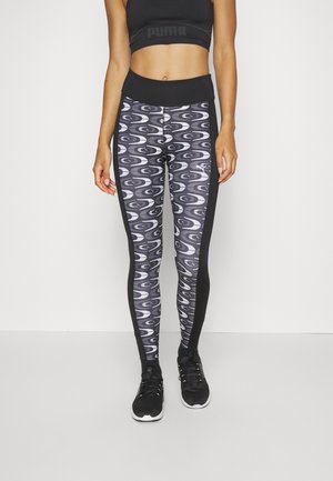 Μαύρες και λευκές κολάν με εκτύπωση κυματος, με ψηλή μέση και στερεές μαύρες πλαϊνές πάνελ. Φοριούνται με μαύρα αθλητικά παπούτσια.