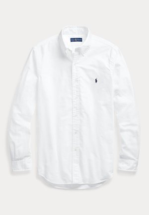 Balta garām piedurknēm krekla ar apkakli, kreisajā krūtīs ar mazu tumši zilu izšūtu Ralph Lauren Polo logotipu.