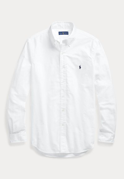 Camisa blanca de manga larga con botones y cuello, con pequeño logo bordado en azul marino de Ralph Lauren Polo en el pecho izquierdo.
