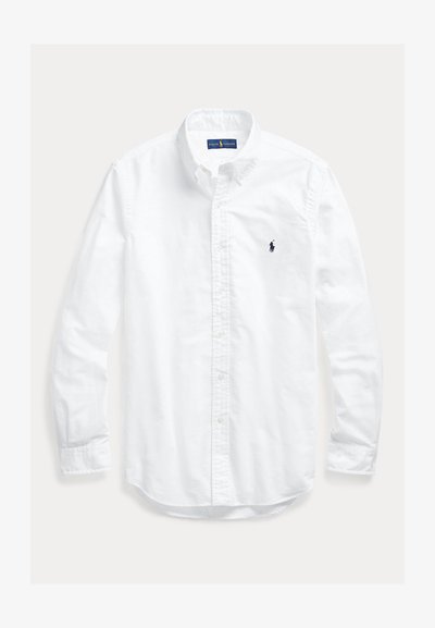 Camisa blanca de manga larga con botones y cuello, con pequeño logo bordado en azul marino de Ralph Lauren Polo en el pecho izquierdo.