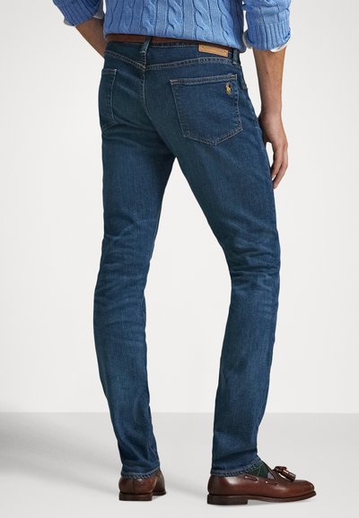 Calças de ganga azuis para homem com corte justo, ligeiro desvanecimento e um único bolso traseiro com logótipo. Detalhes costurados perto do cós.