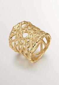 Anillo de oro con un intrincado diseño trenzado que presenta espacios abiertos, textura suave y bordes curvados, reflejando la luz con un acabado brillante.