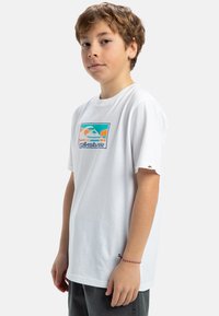 Vit bomull t-shirt med en färgglad grafisk design som föreställer berg och vågor, korta ärmar, och en liten logotyp från varumärket på ärmen.